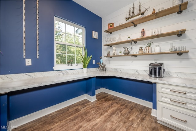 interior space featuring blue cabinets, light stone countertops, and dark hardwood / wood-style flooring