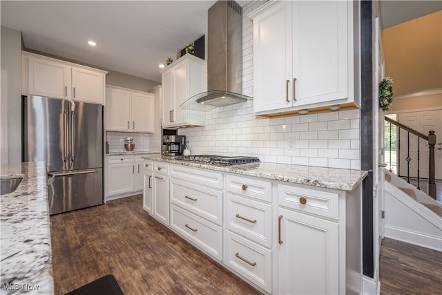 kitchen featuring dark wood-type flooring, wall chimney exhaust hood, appliances with stainless steel finishes, and white cabinetry