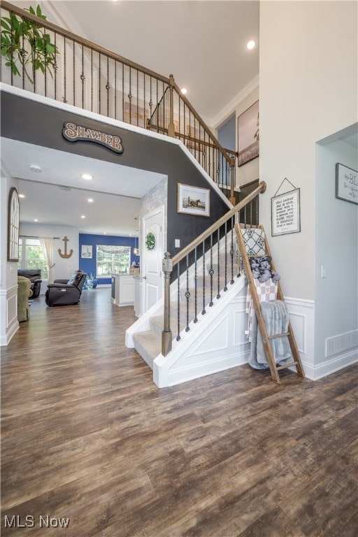 stairs featuring wood-type flooring and a high ceiling