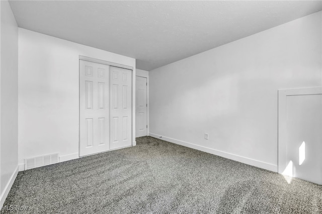 unfurnished bedroom with a textured ceiling, carpet flooring, and a closet