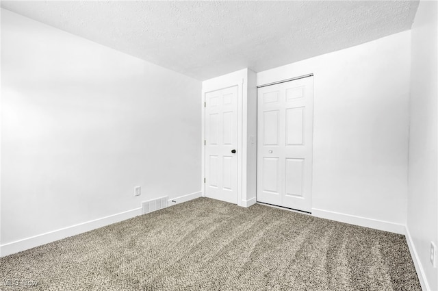 unfurnished bedroom featuring a closet, a textured ceiling, and carpet