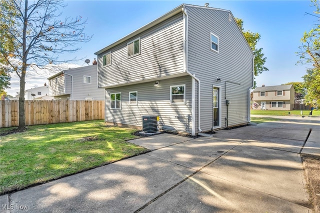 back of property with cooling unit, a patio area, and a lawn