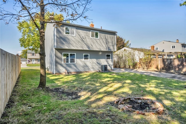 back of property featuring a yard, central AC, and a fire pit