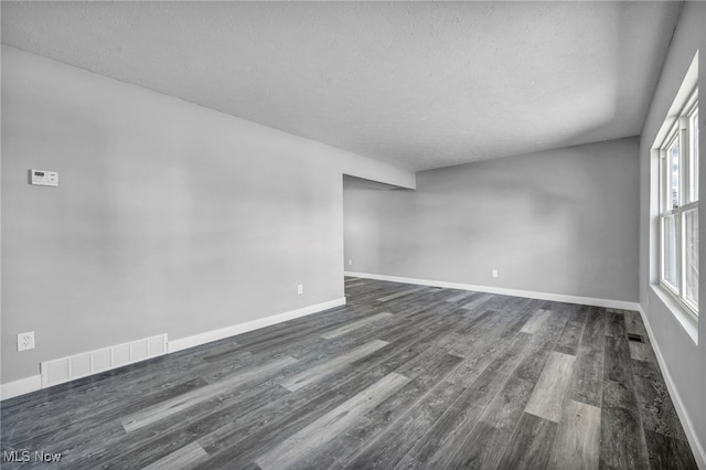 unfurnished room featuring dark wood-type flooring and a textured ceiling