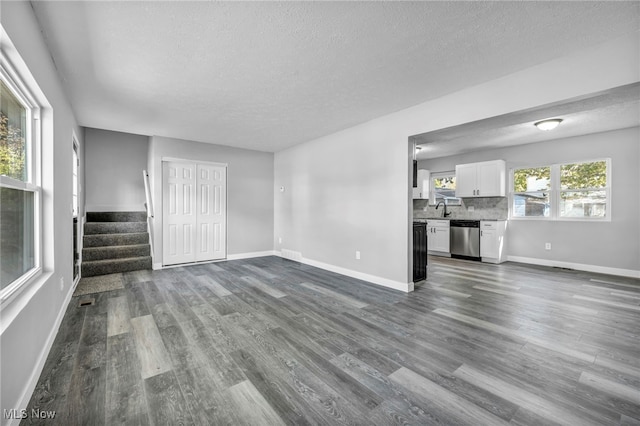 unfurnished living room with a textured ceiling, sink, and dark wood-type flooring