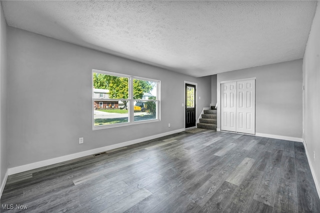 unfurnished room with a textured ceiling and dark hardwood / wood-style flooring