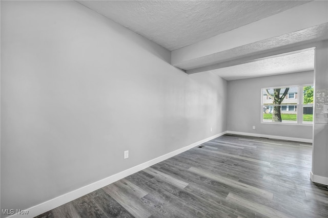 spare room with a textured ceiling and dark hardwood / wood-style floors