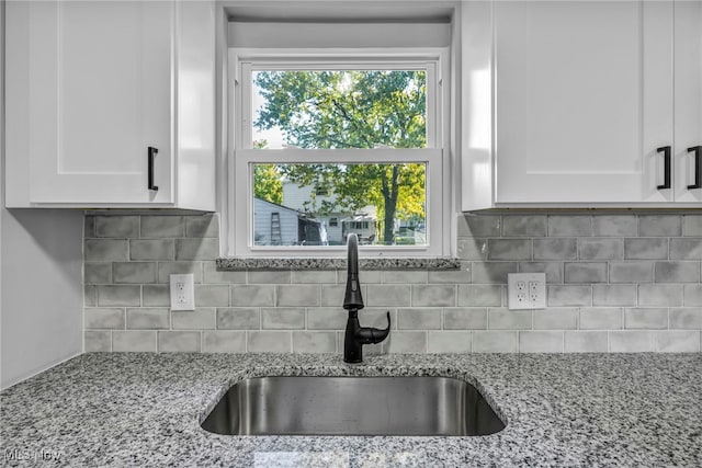 kitchen featuring white cabinetry, light stone counters, sink, and backsplash