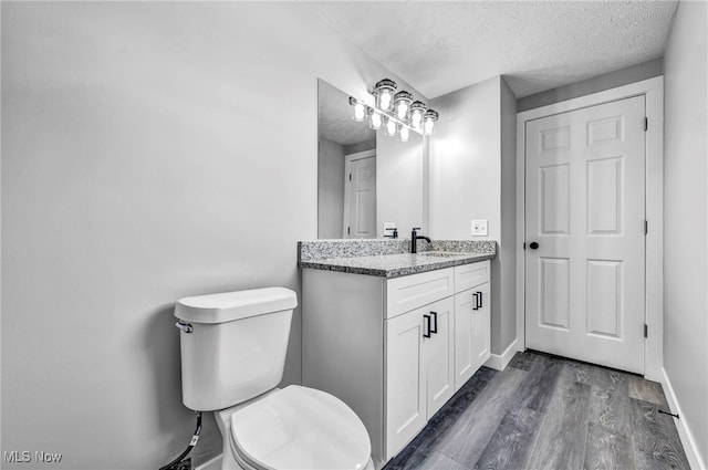 bathroom with toilet, a textured ceiling, vanity, and wood-type flooring