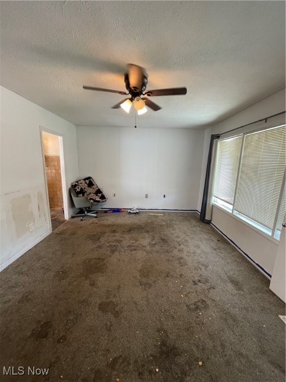 empty room with carpet, ceiling fan, and a textured ceiling