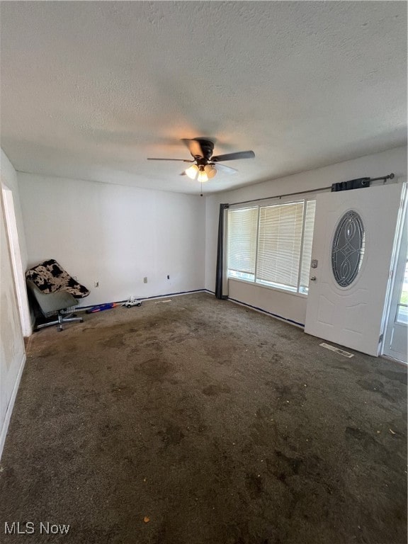 foyer featuring ceiling fan, a textured ceiling, and carpet floors