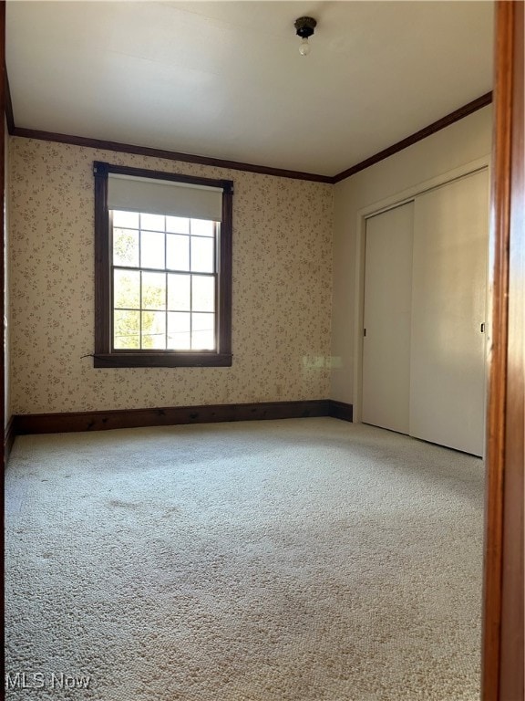 unfurnished bedroom featuring a closet, carpet flooring, and crown molding