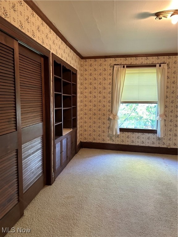 carpeted spare room featuring crown molding