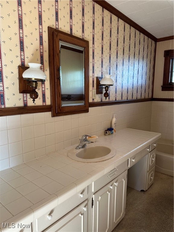 bathroom with vanity, ornamental molding, a washtub, and tile walls