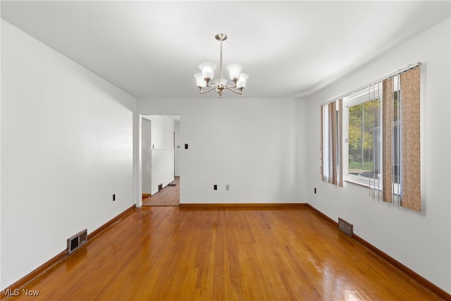 unfurnished room featuring light hardwood / wood-style flooring and an inviting chandelier