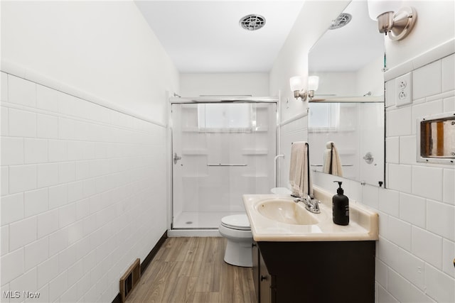 bathroom featuring hardwood / wood-style floors, tile walls, toilet, a shower with shower door, and vanity