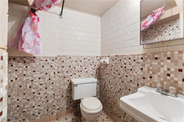 bathroom featuring toilet, tile walls, and sink