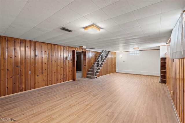 basement with wood walls and wood-type flooring