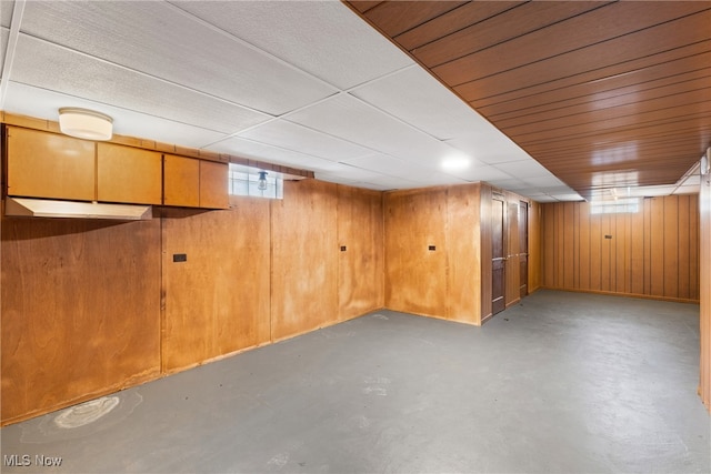 basement with a healthy amount of sunlight and wood walls