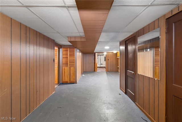 hall with a paneled ceiling and wooden walls