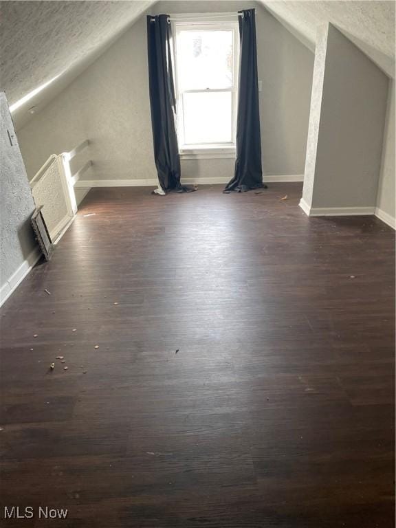 bonus room featuring a textured ceiling, dark hardwood / wood-style floors, and vaulted ceiling