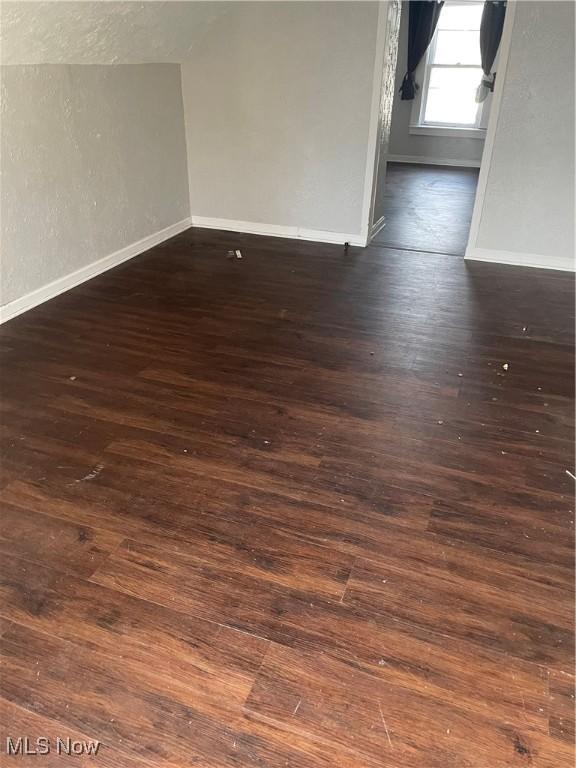 empty room with dark wood-type flooring and vaulted ceiling