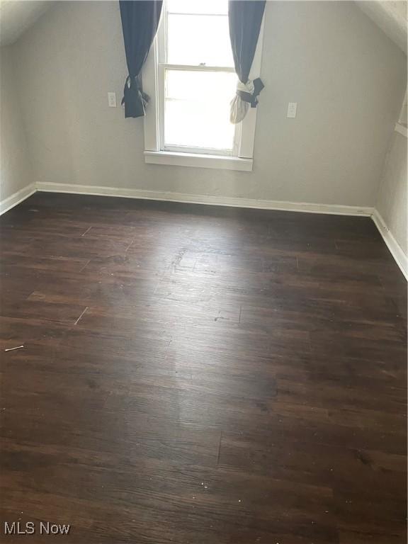 bonus room with dark wood-type flooring and lofted ceiling