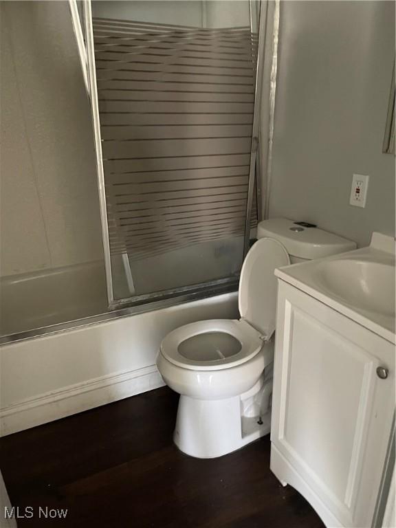 full bathroom featuring combined bath / shower with glass door, wood-type flooring, vanity, and toilet