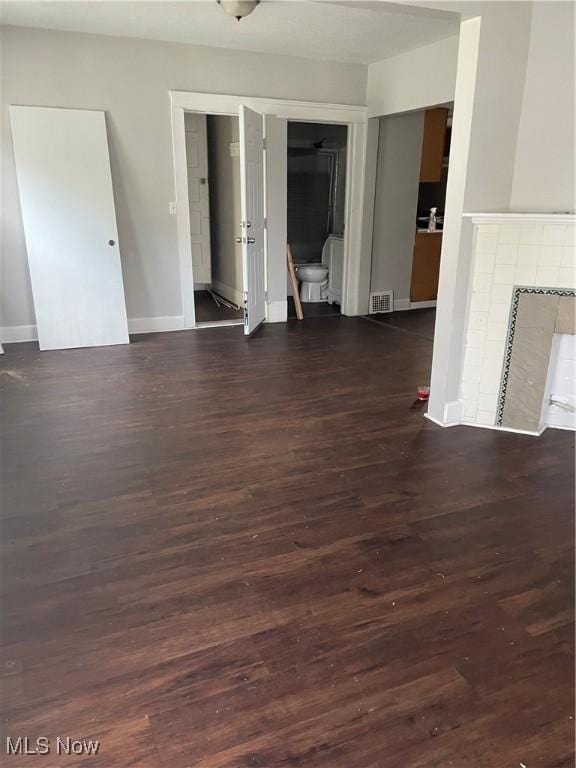 unfurnished room with dark hardwood / wood-style flooring and a tiled fireplace