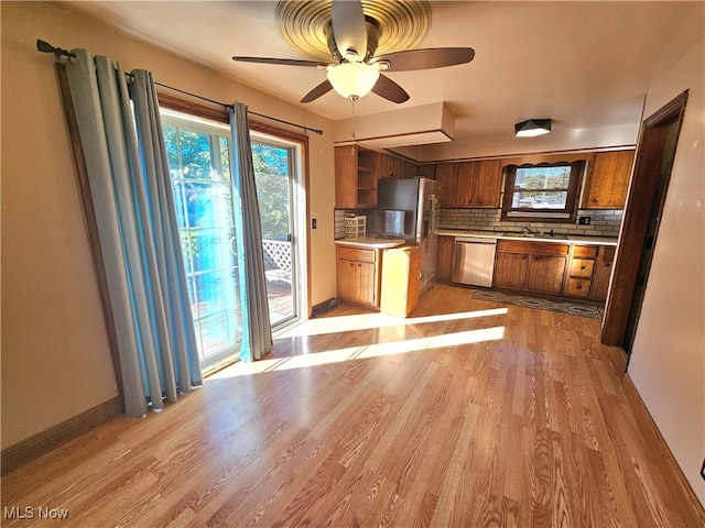 kitchen with decorative backsplash, appliances with stainless steel finishes, light wood-type flooring, and ceiling fan