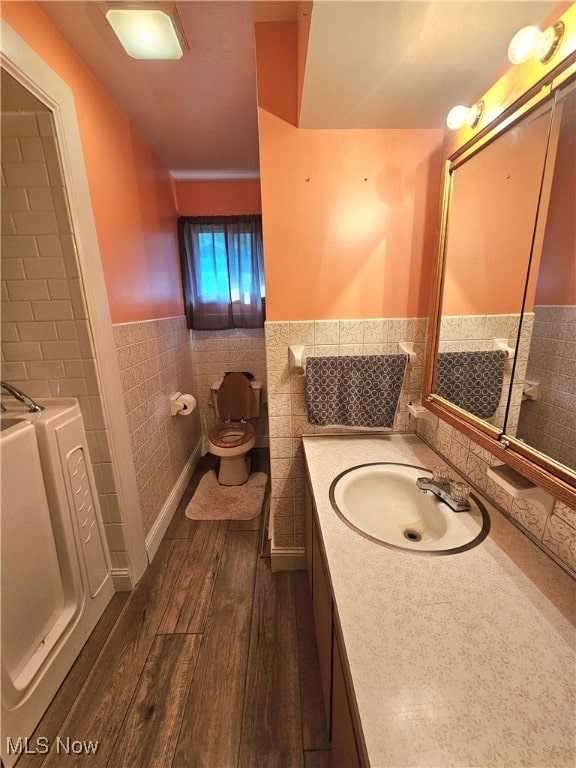 bathroom featuring vanity, hardwood / wood-style flooring, toilet, and tile walls