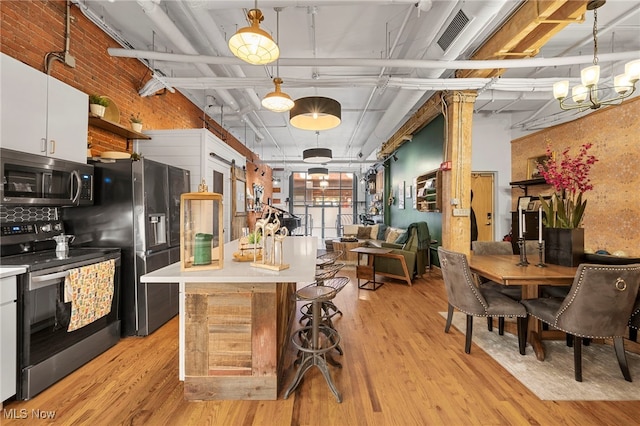 kitchen with white cabinetry, appliances with stainless steel finishes, decorative light fixtures, and light wood-type flooring