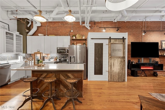 kitchen with a kitchen island, a barn door, hanging light fixtures, and stainless steel appliances