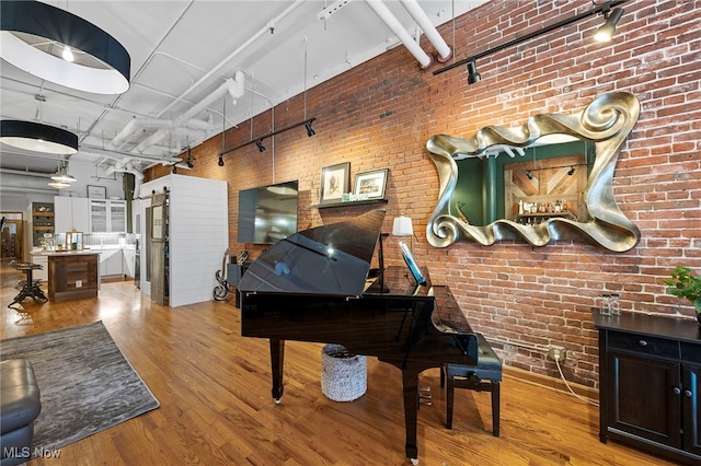 miscellaneous room with brick wall and light hardwood / wood-style flooring