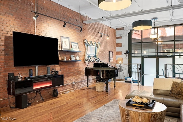 living room with a towering ceiling, brick wall, and wood-type flooring