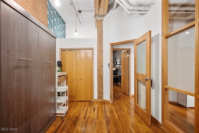 corridor with rail lighting, hardwood / wood-style flooring, and a towering ceiling