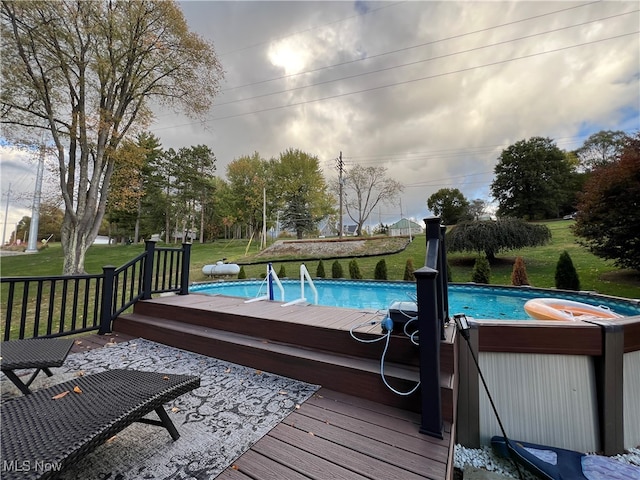 view of pool with a wooden deck and a lawn