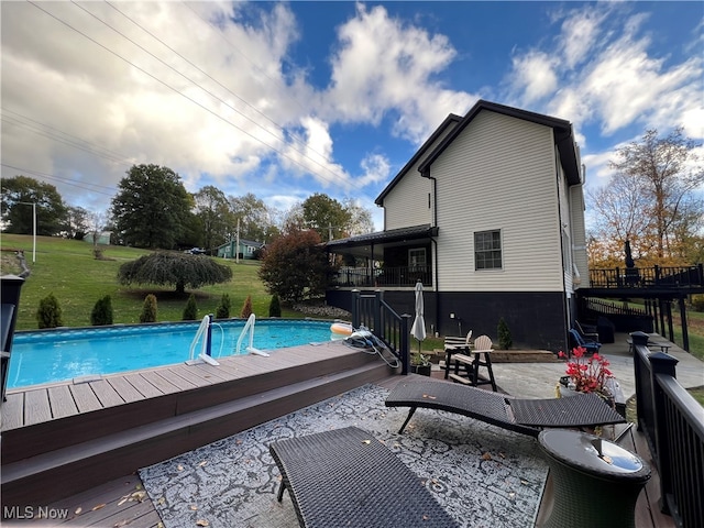 view of pool with a patio, a deck, and a lawn