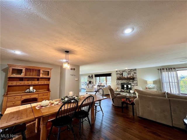 dining room featuring dark hardwood / wood-style floors, a textured ceiling, and a wealth of natural light