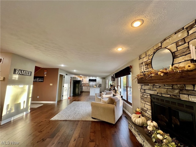 living room with dark wood-type flooring, a fireplace, and a textured ceiling