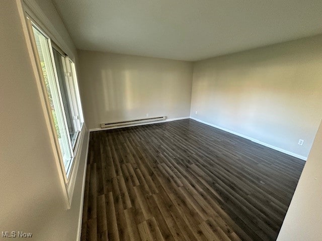 spare room featuring a baseboard radiator and dark hardwood / wood-style floors