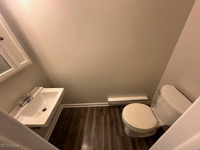 bathroom featuring baseboard heating, sink, hardwood / wood-style flooring, and toilet