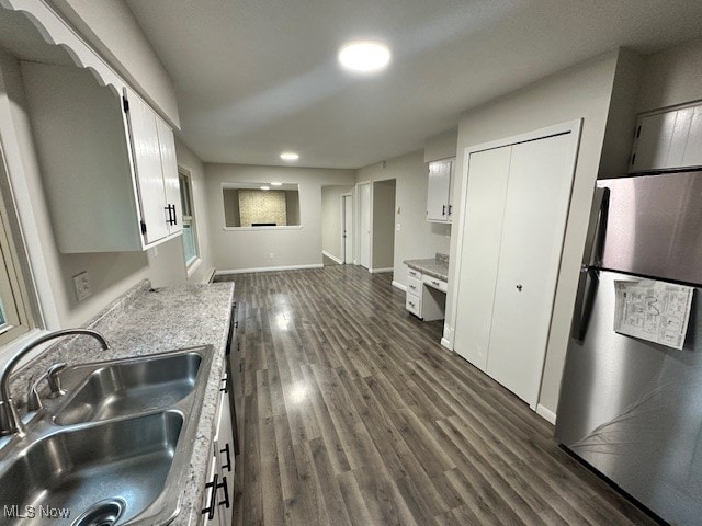 kitchen with white cabinetry, dark hardwood / wood-style floors, sink, and stainless steel refrigerator