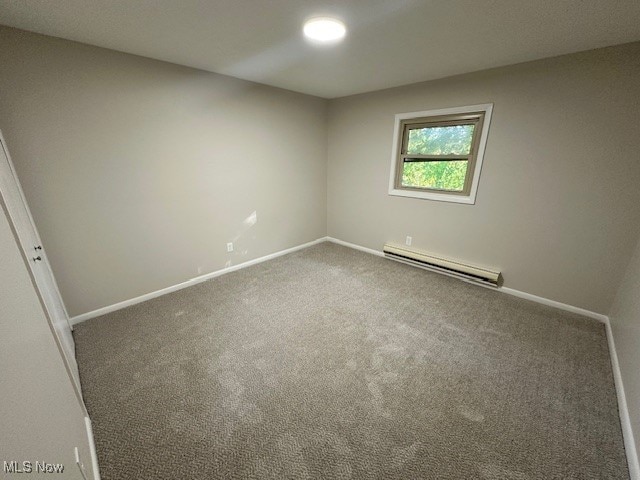 carpeted empty room with a baseboard heating unit