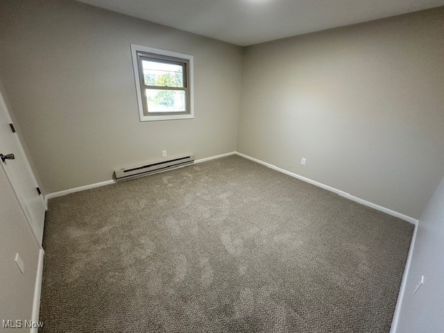 carpeted spare room featuring baseboard heating