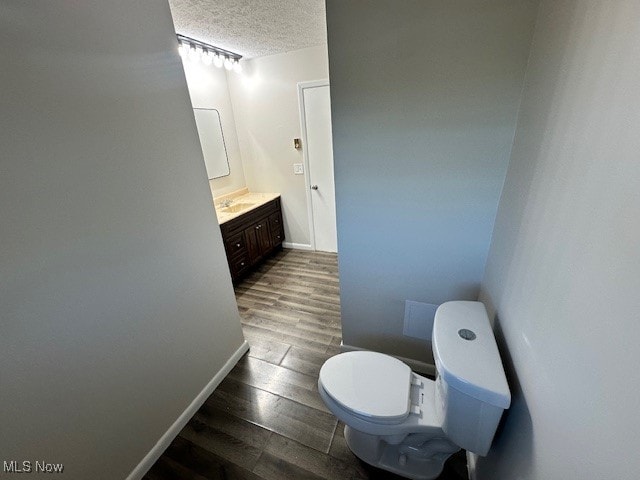 bathroom with vanity, a textured ceiling, hardwood / wood-style flooring, and toilet