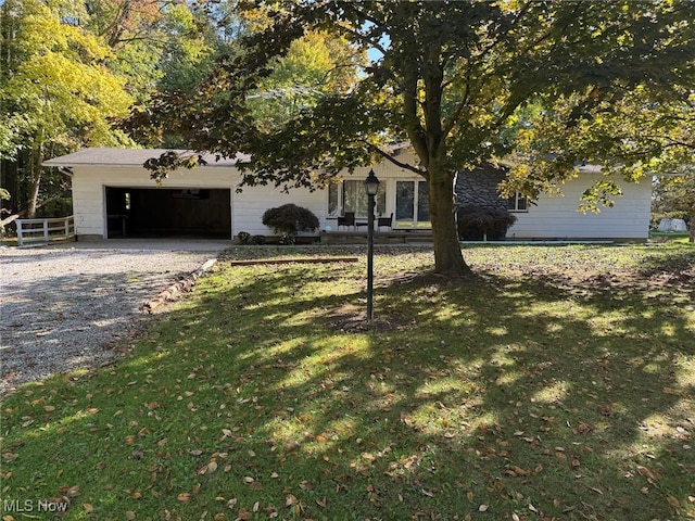 view of property hidden behind natural elements with a front yard and a garage