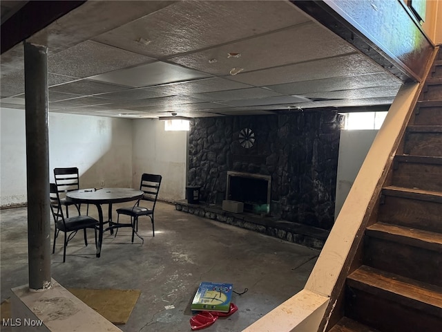 basement featuring a drop ceiling, plenty of natural light, and a fireplace