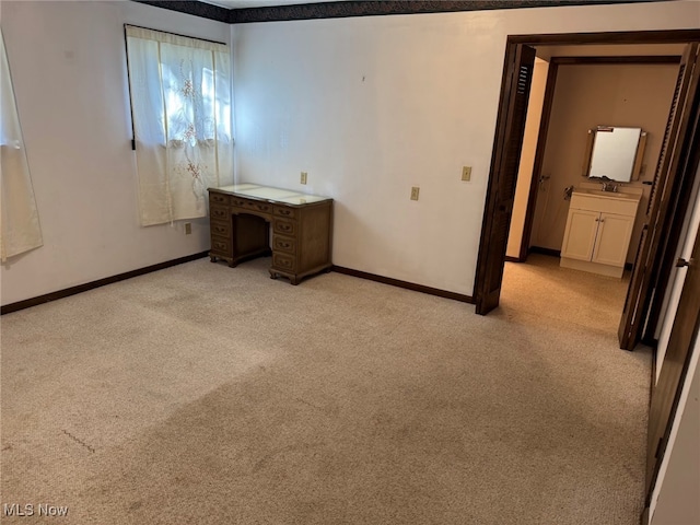 unfurnished bedroom featuring light carpet and ensuite bath