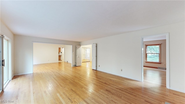 empty room with baseboard heating and light wood-type flooring